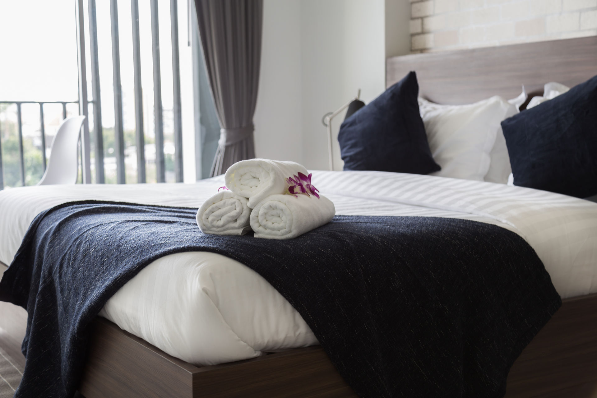 Bett im Hotelzimmer mit frischer Bettwäsche, darauf Frottierhandtücher