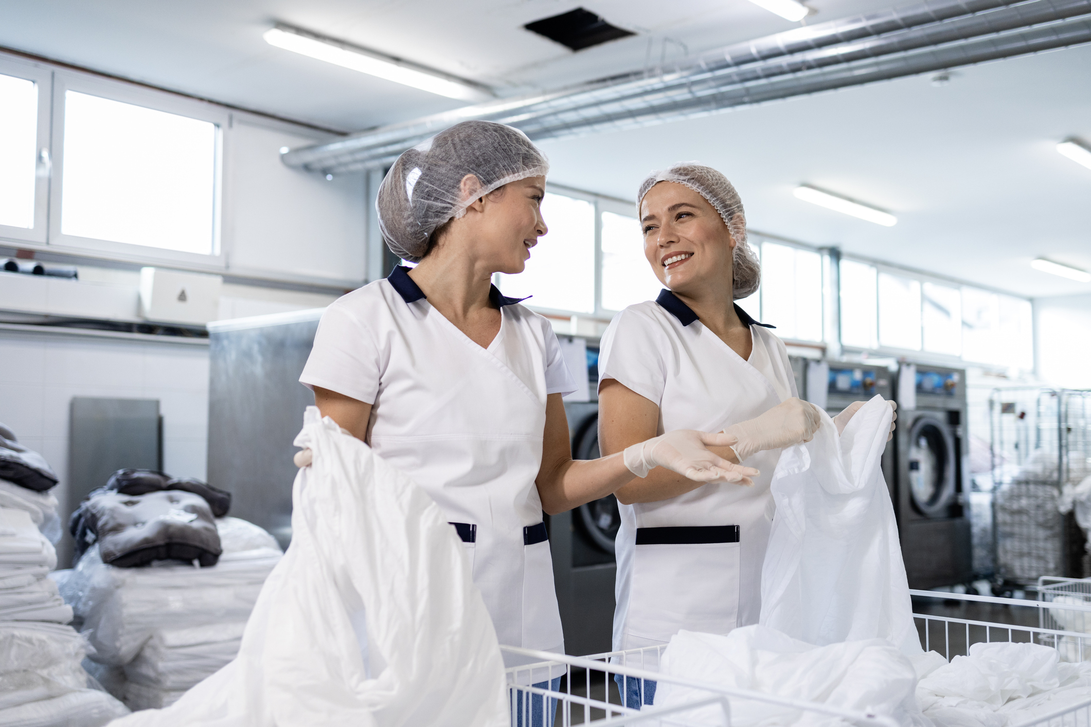 Zwei Mitarbeitende sortieren in der Wäscherei Bettwäsche.