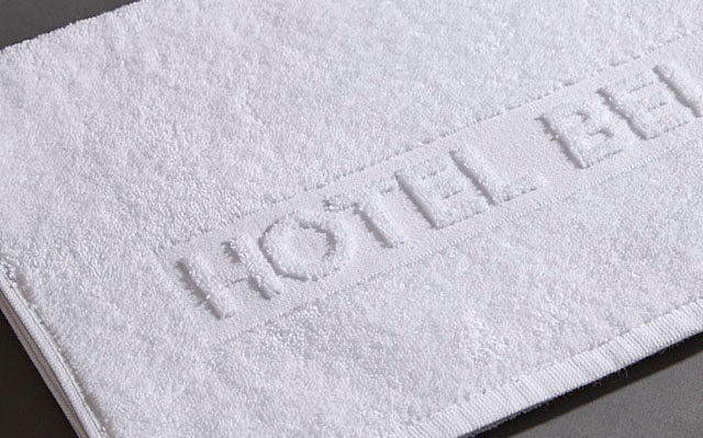 Ein weißes Handtuch befindet sich flach auf einer grauen Oberfläche.