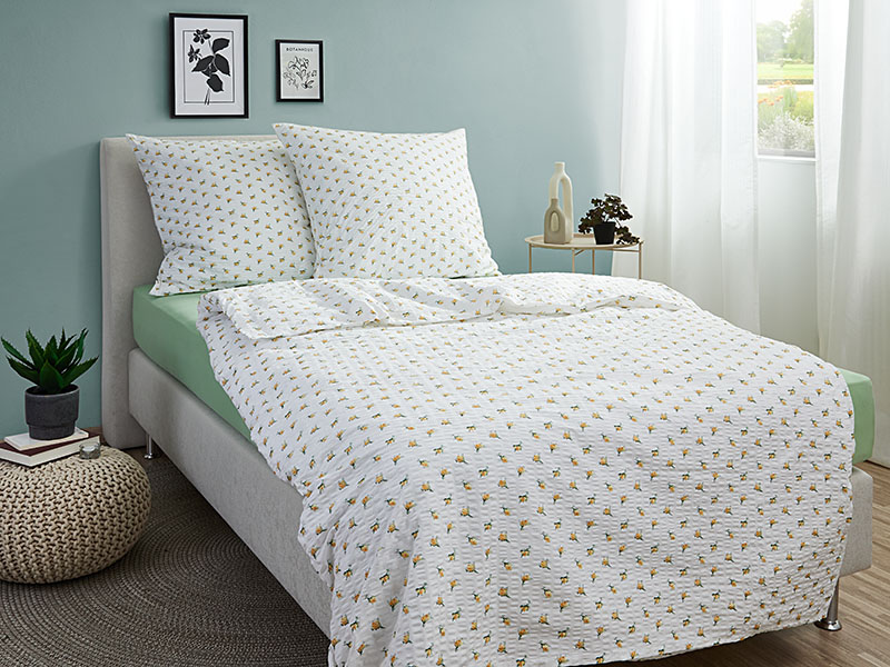 Seersucker-Bettwäsche Landhausrose RV | 80x80 + 135x200, gelb Bett mit Seersucker-Bettwäsche in Weiß mit gelben Rosenmotiven, kombiniert mit grünem Spannbettlaken in einem hellen, modern eingerichteten Schlafzimmer.