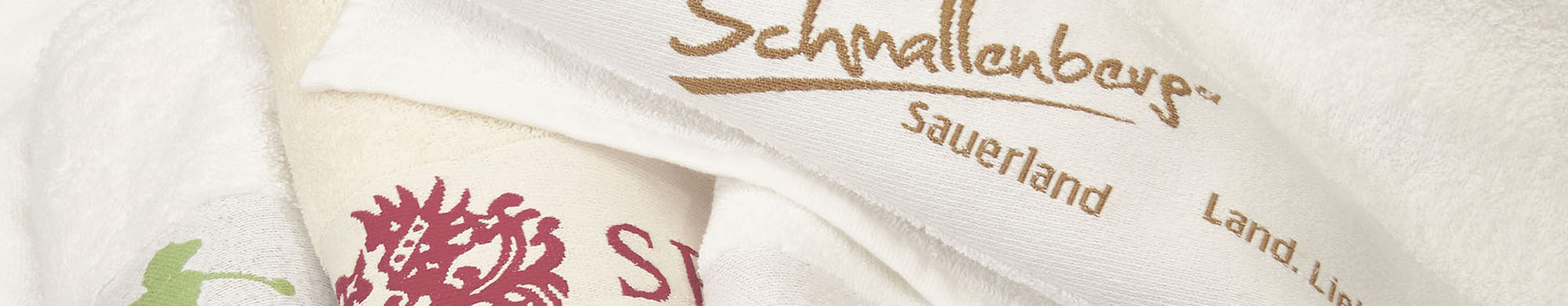 Weiße Handtücher, gefaltet, mit aufgedrucktem Text und Logo im Hintergrund.