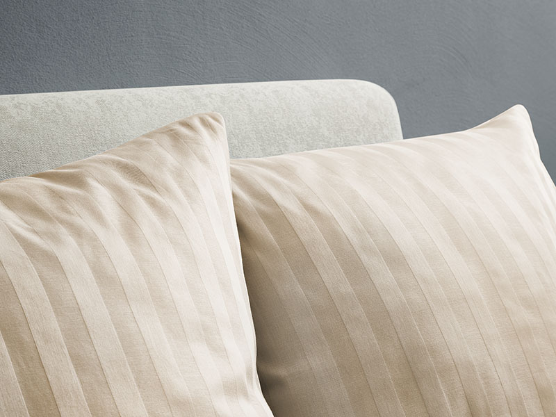 Hotel-Streifendamast Bettwäsche | 80x80, creme - Stück Zwei cremefarbene Kissen mit Streifendamast-Bezug vor einem hellen Polsterkopfteil, die dezente Webstruktur und den Glanz des Stoffes betonend.